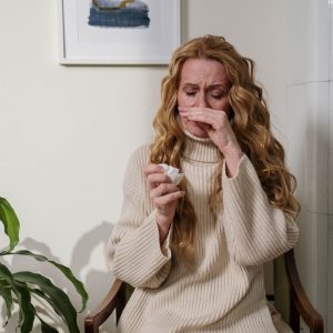 woman holding tissue and sniffling